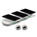 A black universal Qi wireless charging pad on a wooden desk next to a smartphone.