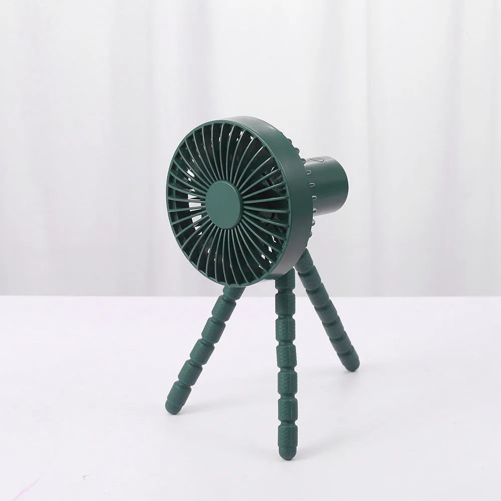 Small black adjustable tripod desktop fan with bending neck and clip, shown on a desk.