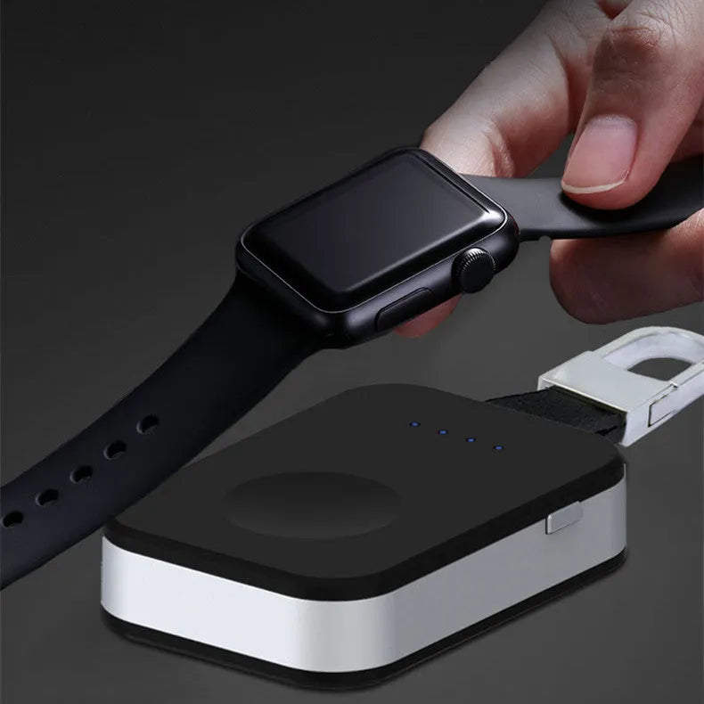 Black Apple Watch keychain power bank with wireless charging pad next to an Apple Watch.