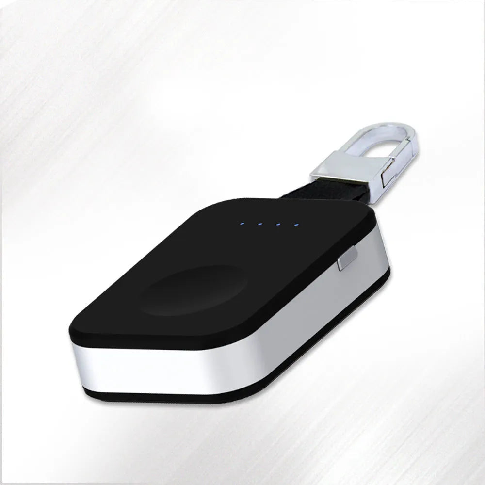 Black Apple Watch keychain power bank with wireless charging pad next to an Apple Watch.