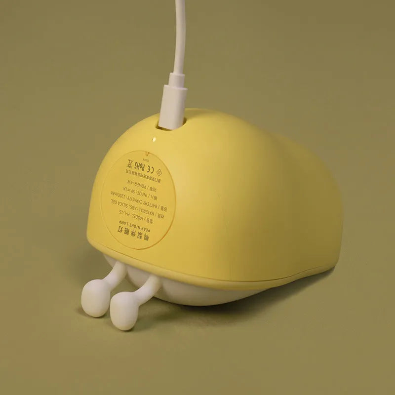 Yali pear-shaped silicone night light emitting warm yellow light on a bedside table.