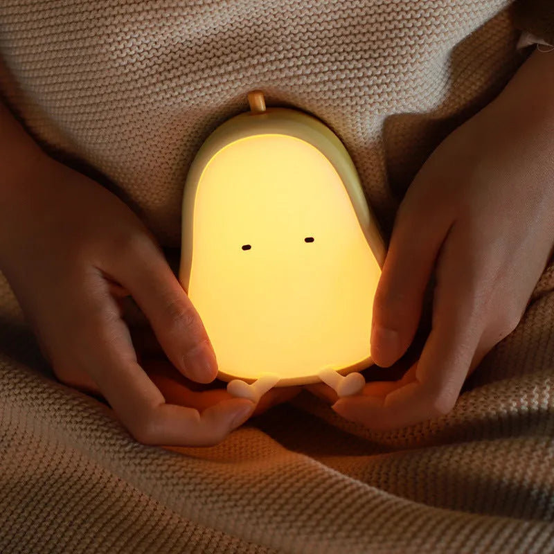 Yali pear-shaped silicone night light emitting warm yellow light on a bedside table.