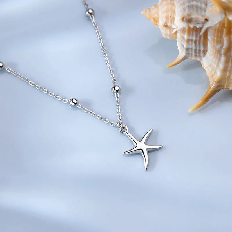Adjustable sterling silver anklet with round beads and a detailed starfish charm on an ankle.