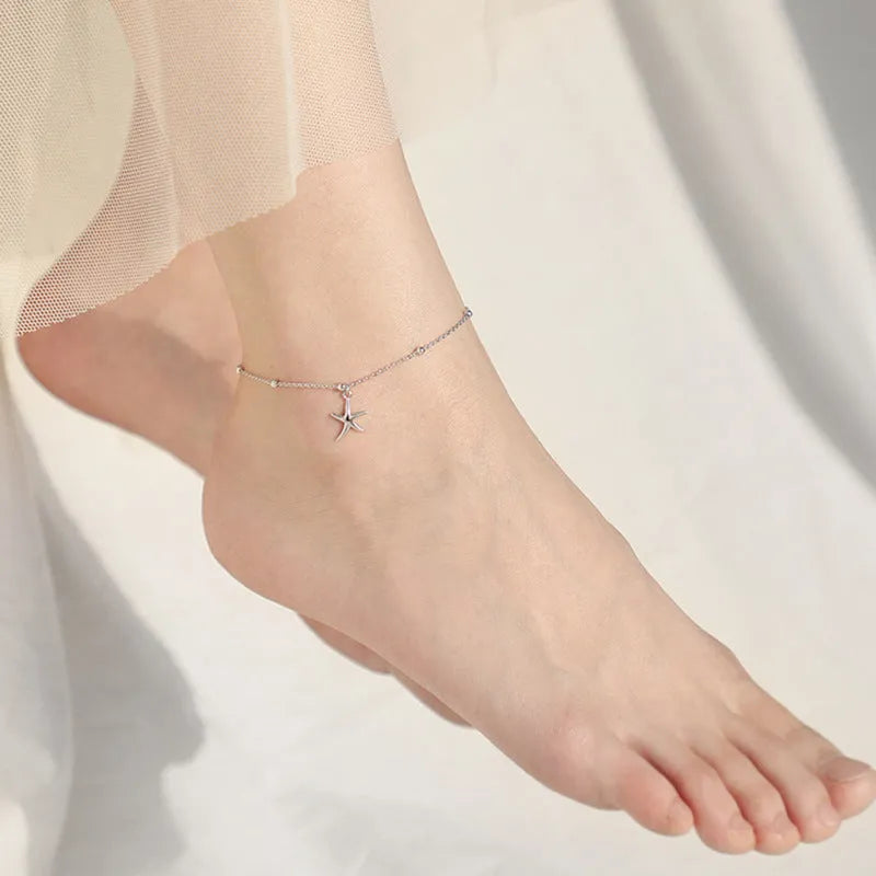 Adjustable sterling silver anklet with round beads and a detailed starfish charm on an ankle.