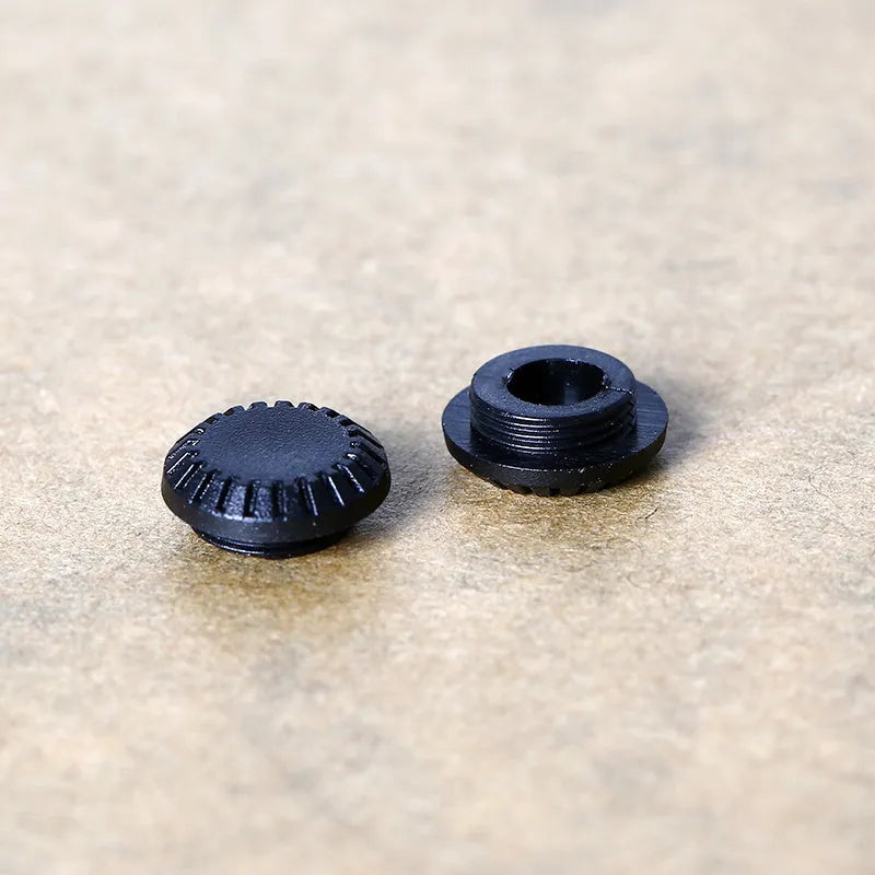 Black plastic camera shutter cover button 1cm diameter on white background