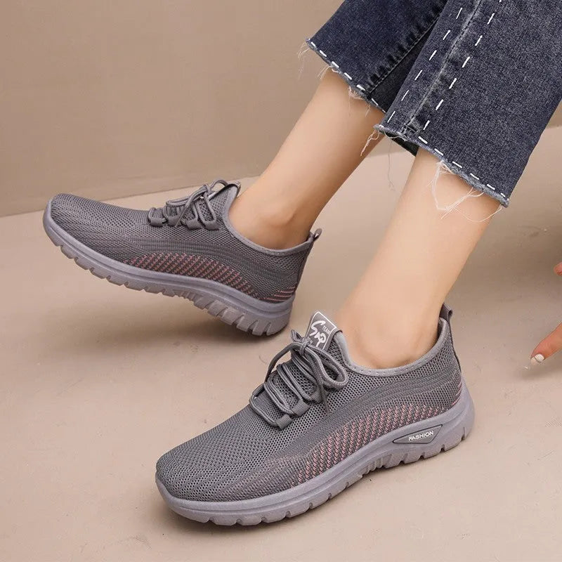 Women's black mesh sneakers with cross strap detail and round toe on a rubber sole.