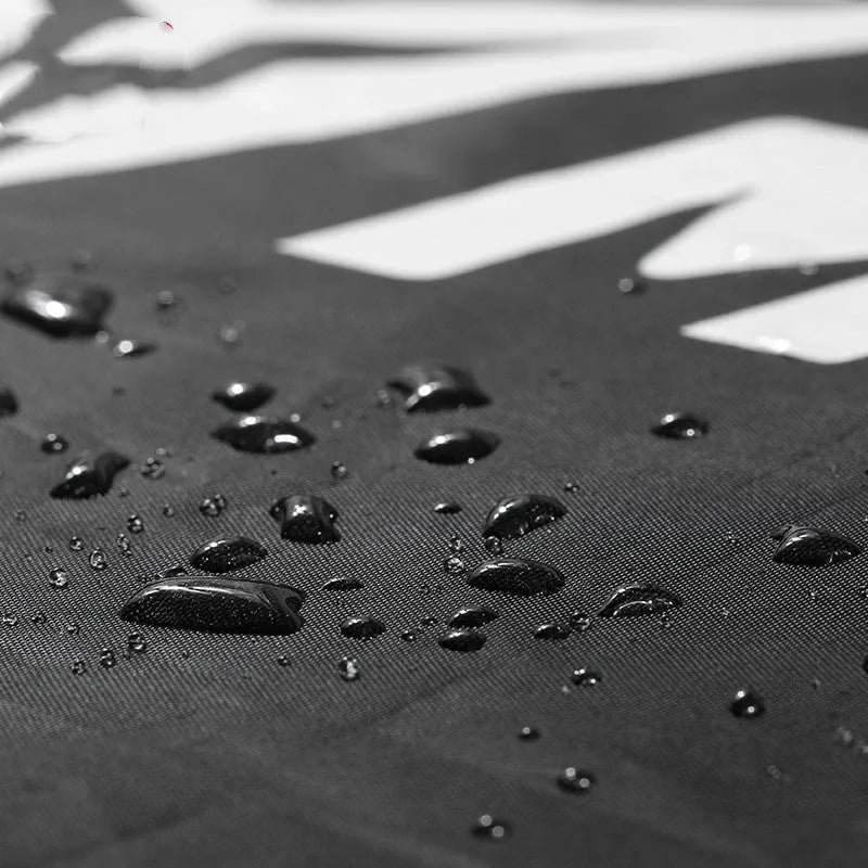 Black motorcycle cover made of 190T polyester and 210D Oxford cloth parked over a scooter outdoors