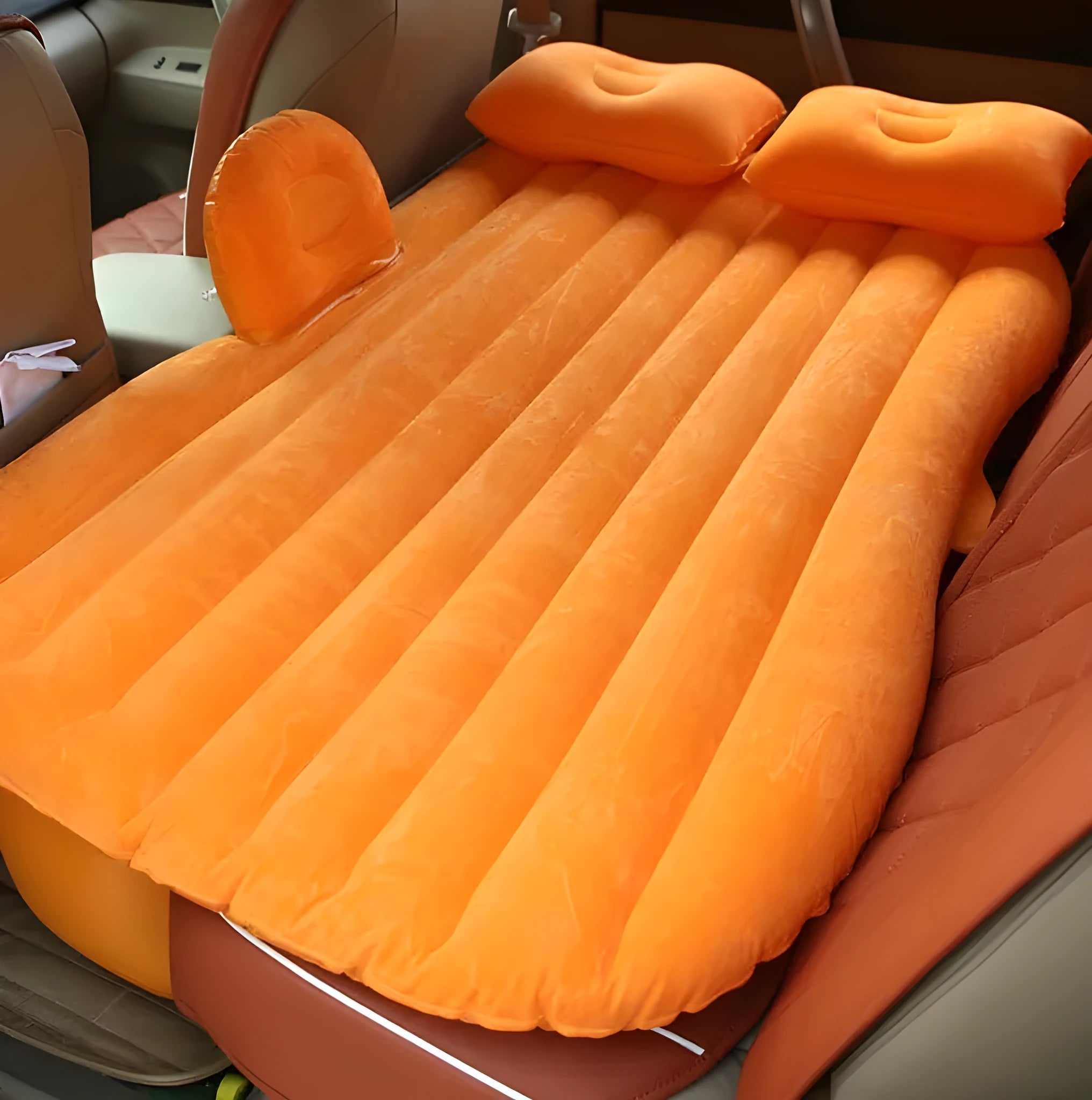 Black car inflatable bed with two pillows, shown inflated in a vehicle's rear compartment.