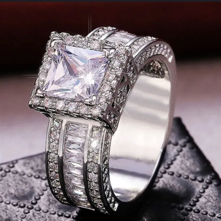 Geometric women's alloy ring with round detail in gold or white electroplated finish on a finger.