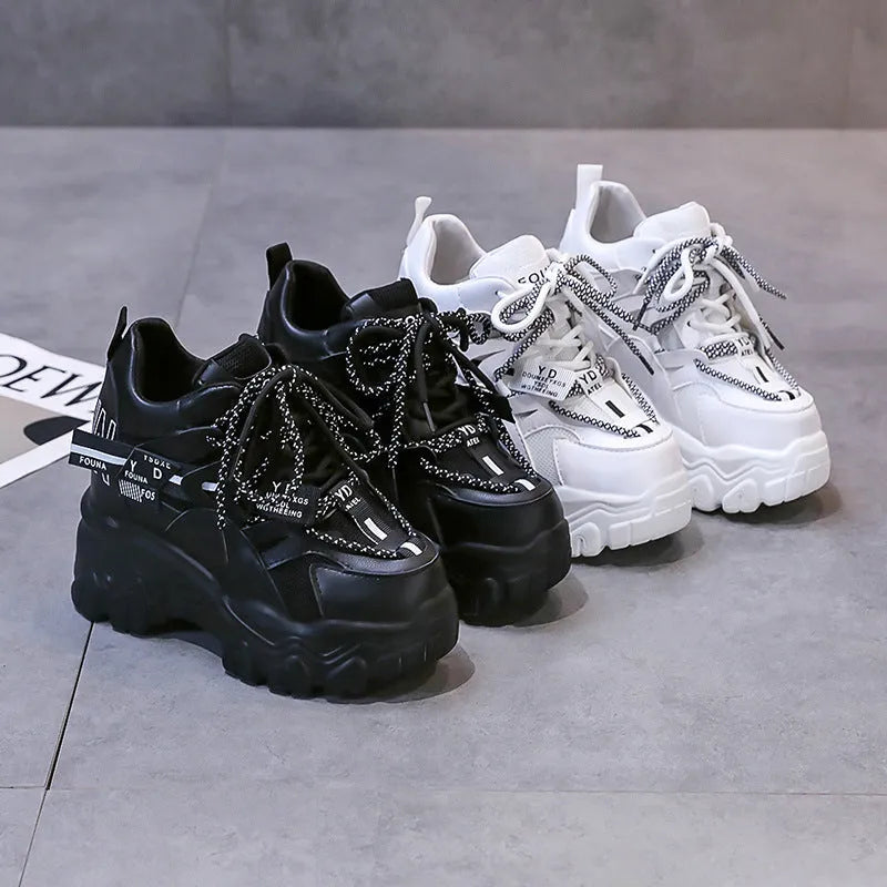 White women's low-top platform sports shoes with a cross-strap over a shallow-cut collar and a thick rubber sole.