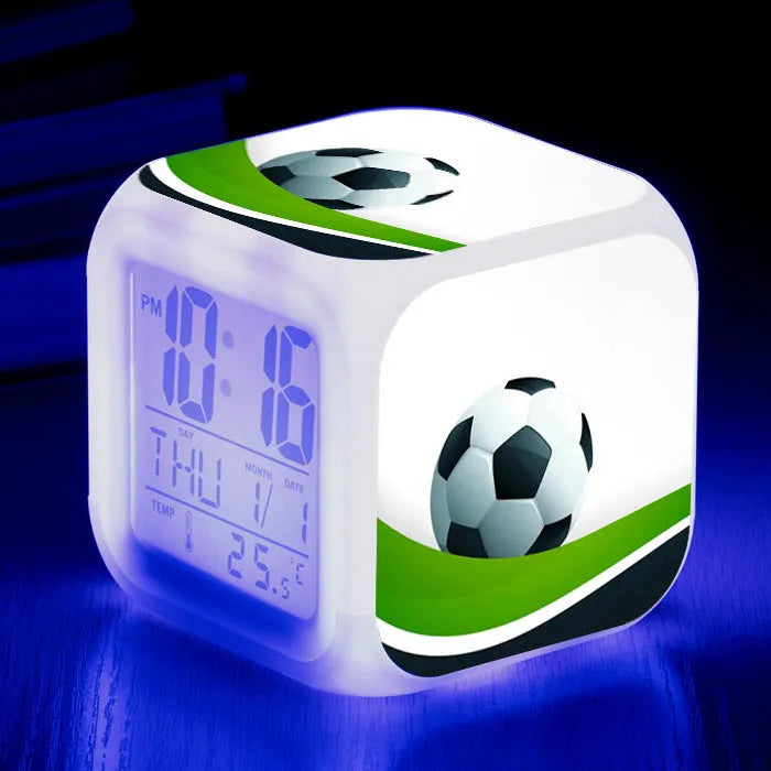 Square cartoon football pattern children's alarm clock with mute alarm on a bedside table.