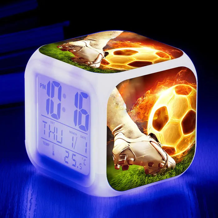 Square cartoon football pattern children's alarm clock with mute alarm on a bedside table.
