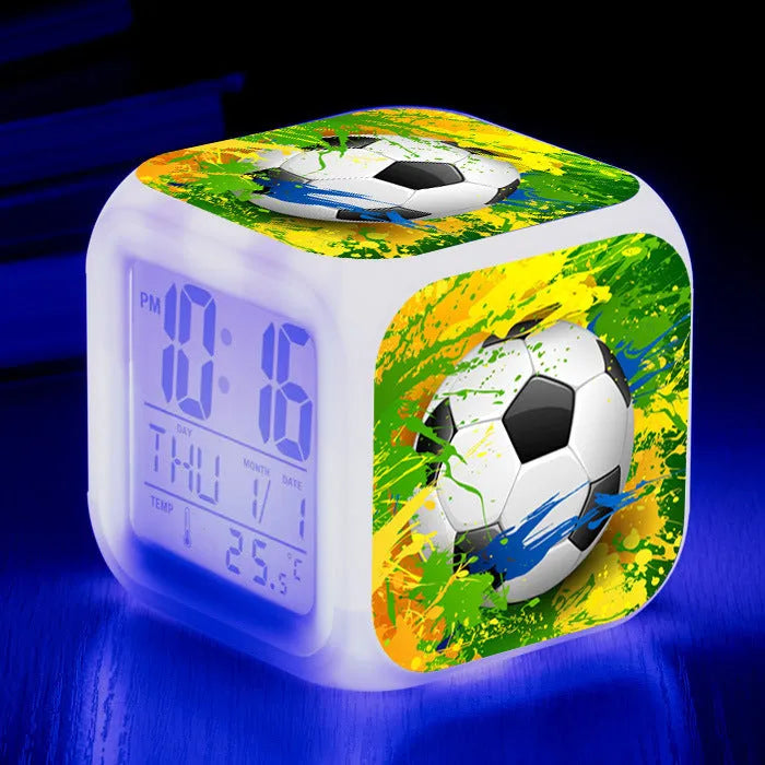 Square cartoon football pattern children's alarm clock with mute alarm on a bedside table.