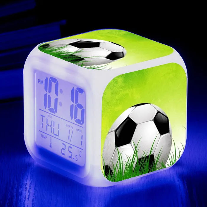 Square cartoon football pattern children's alarm clock with mute alarm on a bedside table.