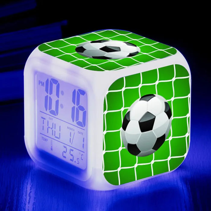 Square cartoon football pattern children's alarm clock with mute alarm on a bedside table.