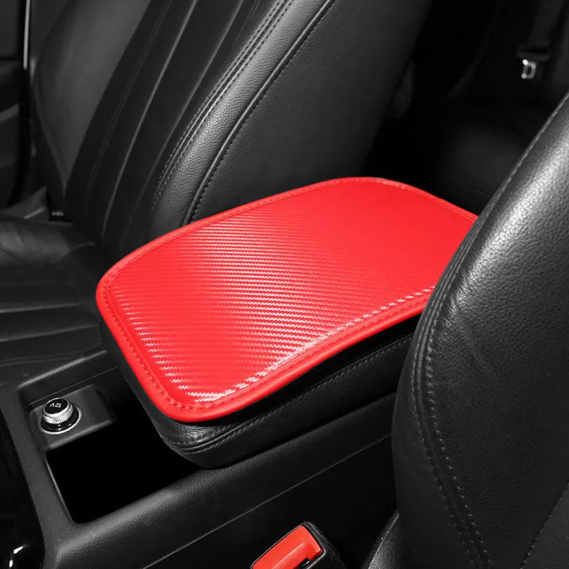 Leather car armrest cushion with carbon fibre pattern in red, shown on a car centre console.