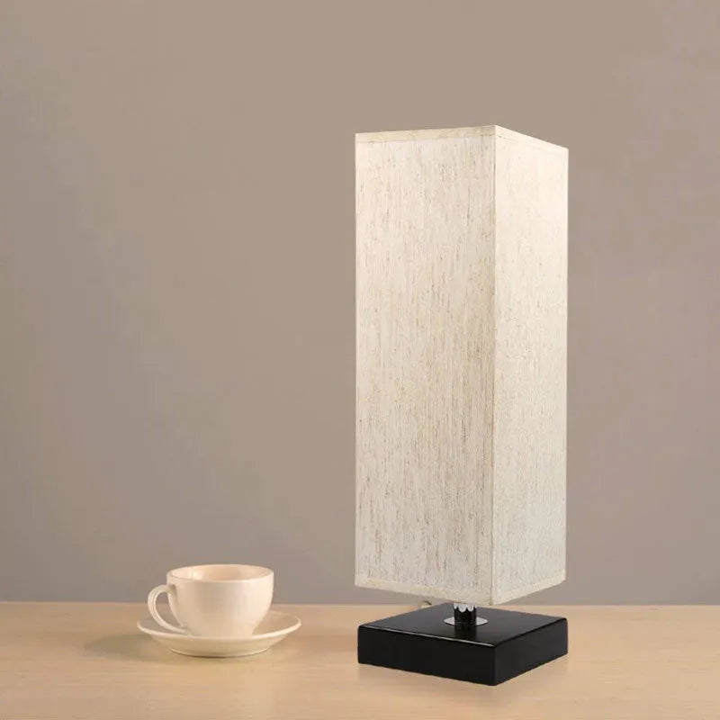 Modern simple square cloth covered table lamp 110V with E26 socket and off-white fabric shade on a desk