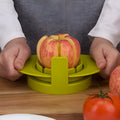Green plastic fruit slicer for apple, tomato and mango cuts with base on a kitchen counter