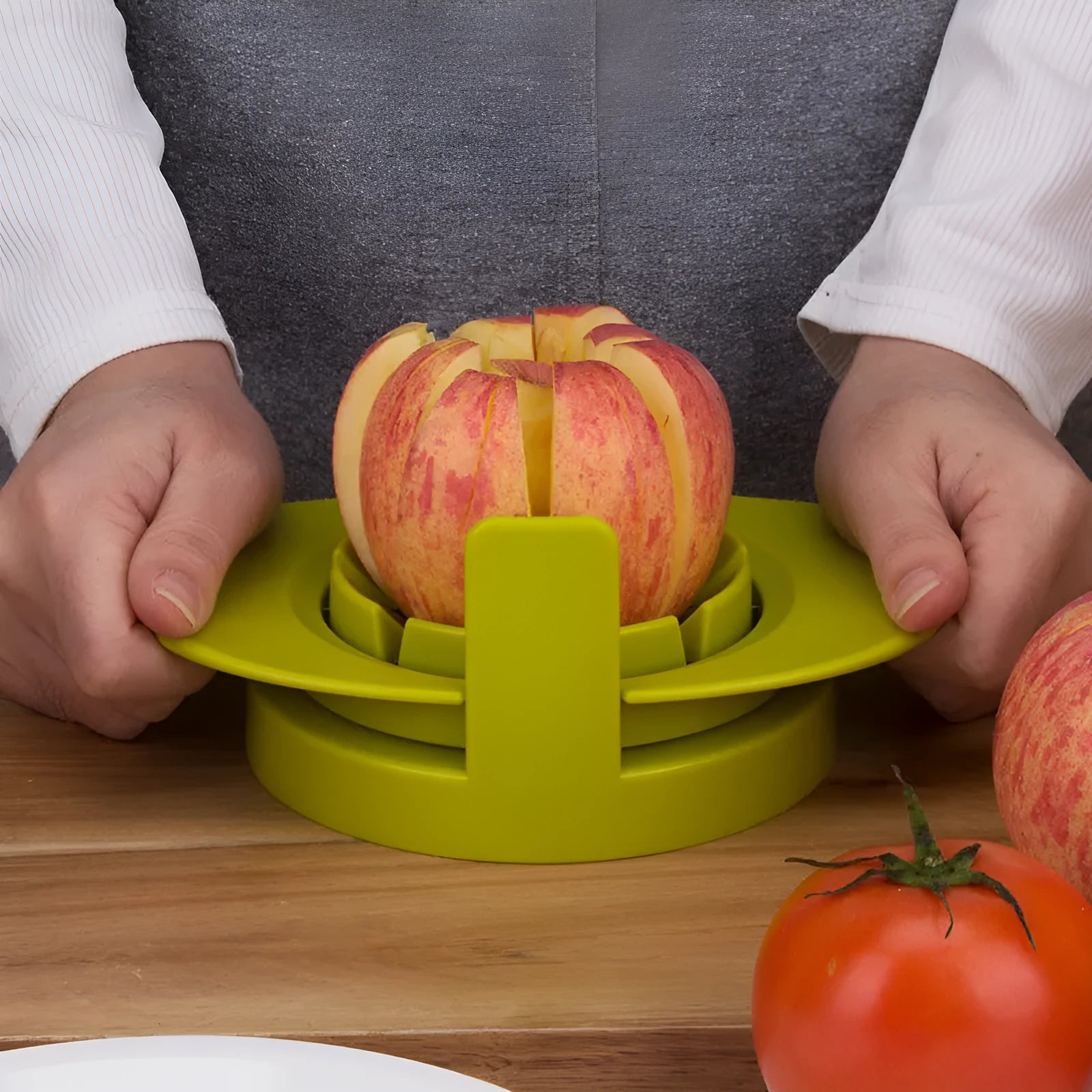 Green plastic fruit slicer for apple, tomato and mango cuts with base on a kitchen counter