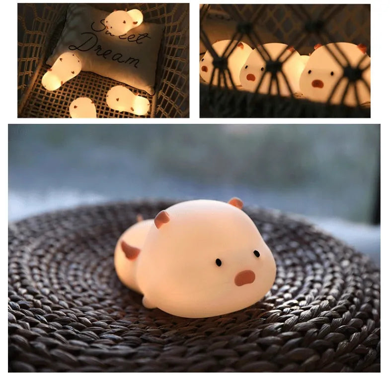 Pink silicone night light in the shape of a sleeping pig on a table.