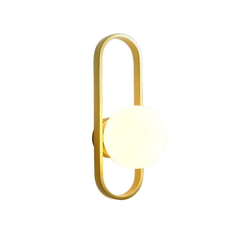 Minimalist circular wall lamp with glass shade on iron arm, in black finish, mounted beside a bed.