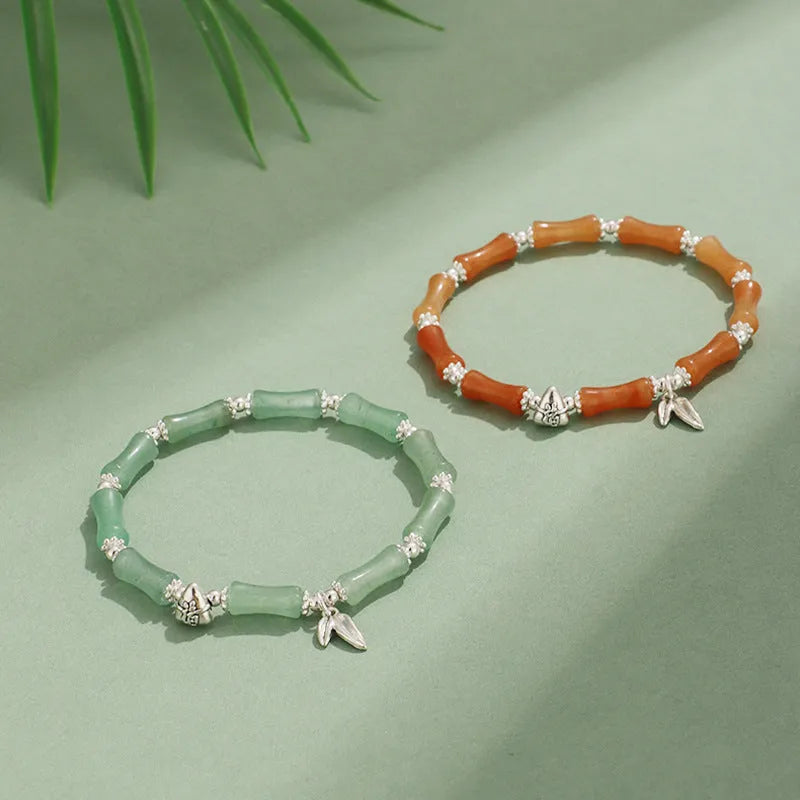 Women's green aventurine crystal bracelet with bamboo, strawberry quartz, and jade beads on wrist.