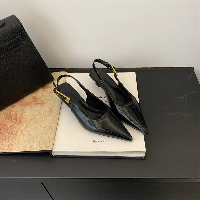 Black leather pointed toe women's shoes with a thin low heel and an ankle strap.