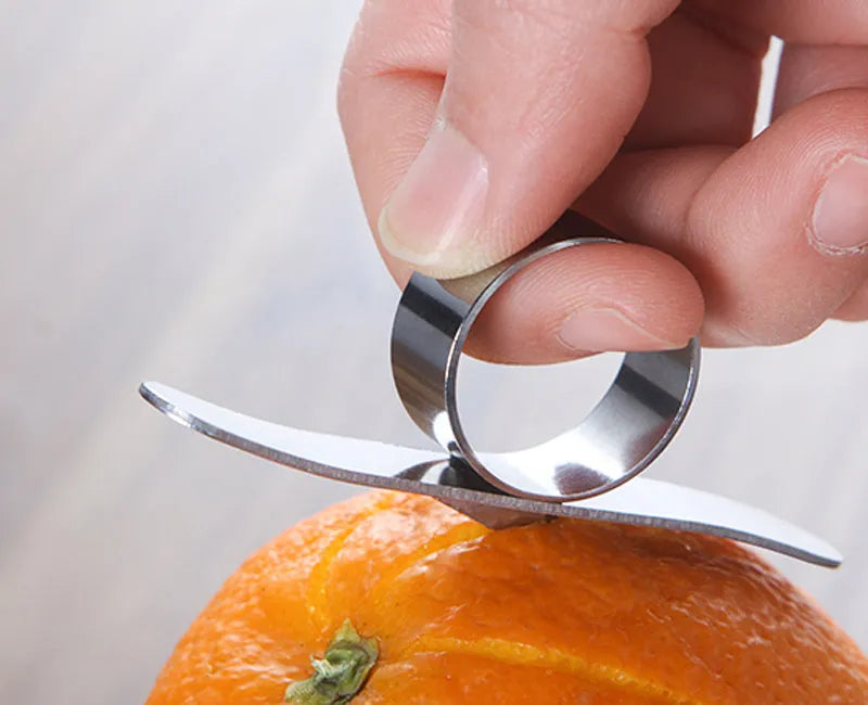 Silver stainless steel kitchen peeler tool with a finger ring for peeling oranges and citrus fruit.