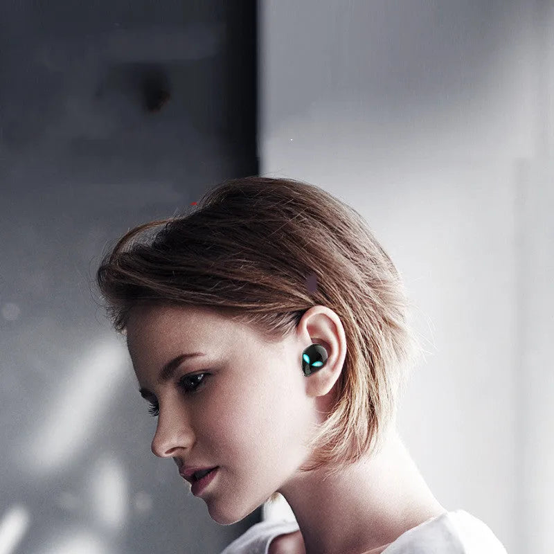 Creative Outer T8 Starman alien-shaped Bluetooth earbuds with LED lights next to their wireless charging case.