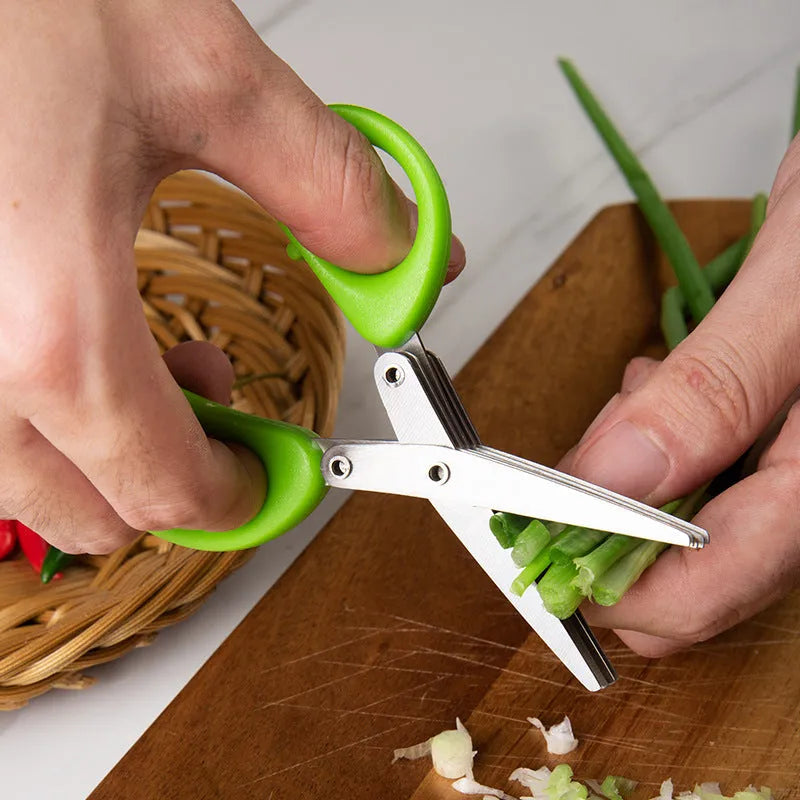 Stainless steel multi-layer kitchen scissors for cutting green onions and herbs on a chopping board.