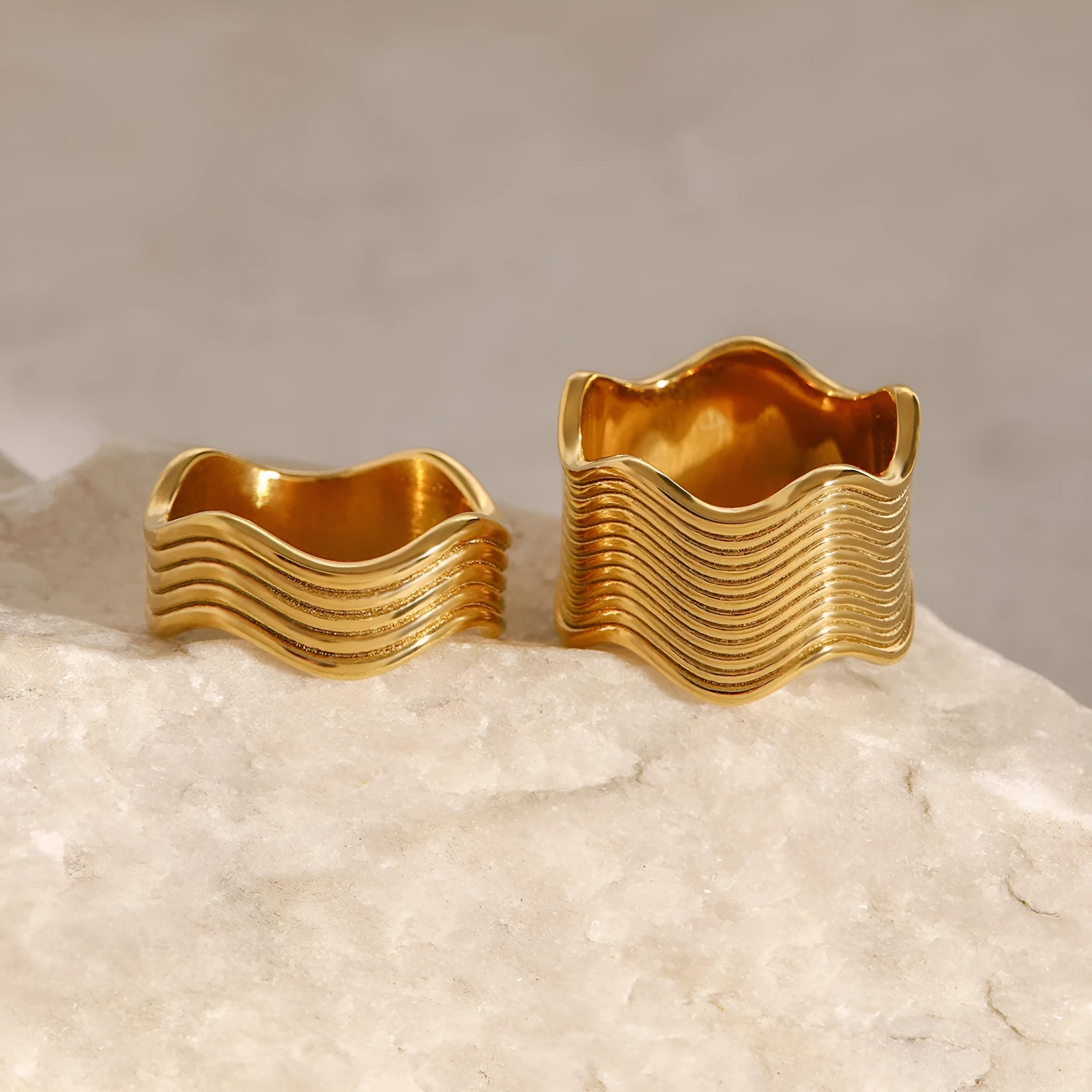 Stainless steel women's ring with wide geometric wave pattern in silver or gold tone.
