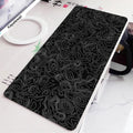 Large black and white gaming mouse pad with non-slip rubber bottom and cloth cover on a desk