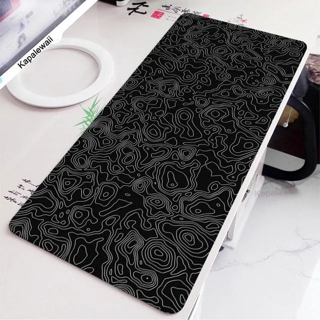Large black and white gaming mouse pad with non-slip rubber bottom and cloth cover on a desk