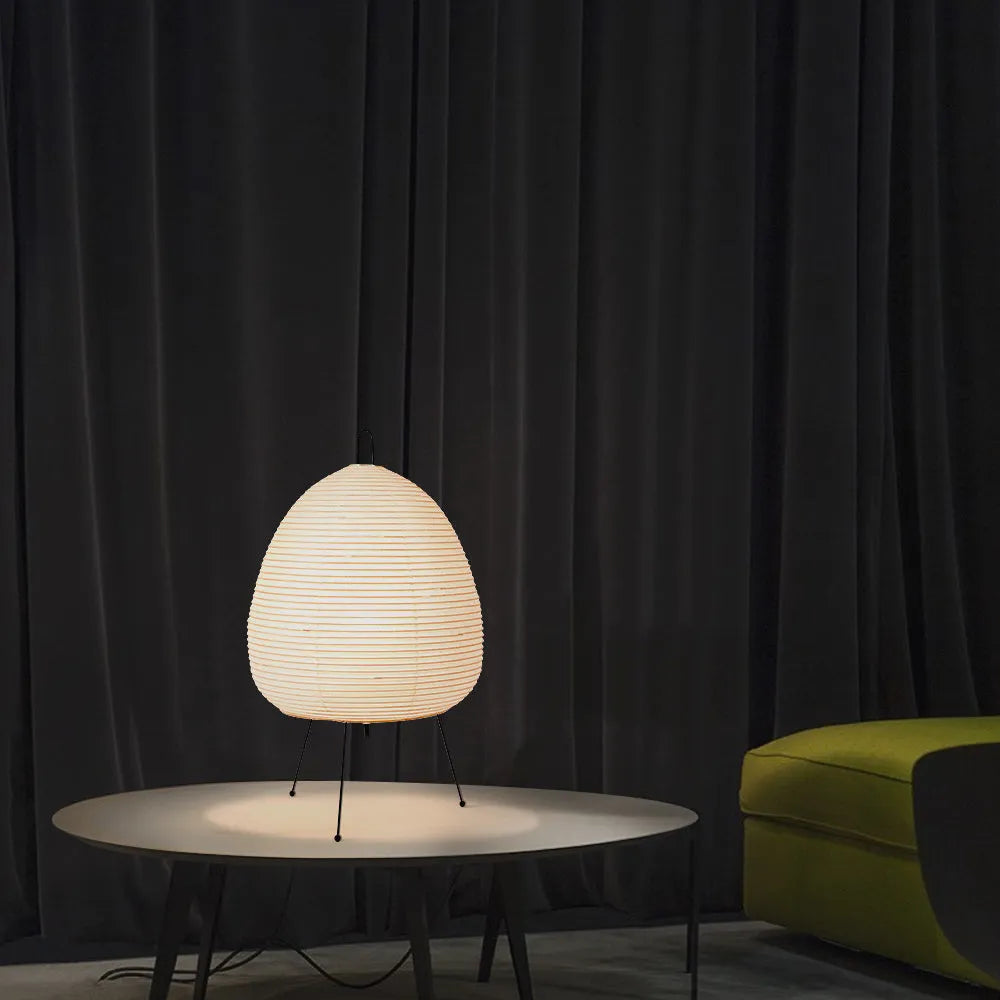Japanese style table lamp with a white handmade rice paper lantern shade and aluminium base on a wooden table.