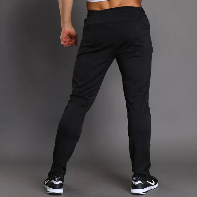 Black slim-fit running fitness trousers with reflective printing and zipper pockets on a model