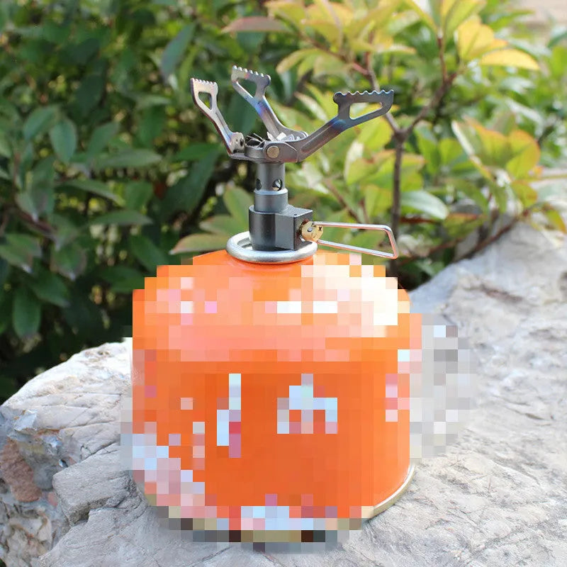Compact one-piece propane camping stove on a rocky outdoor surface.
