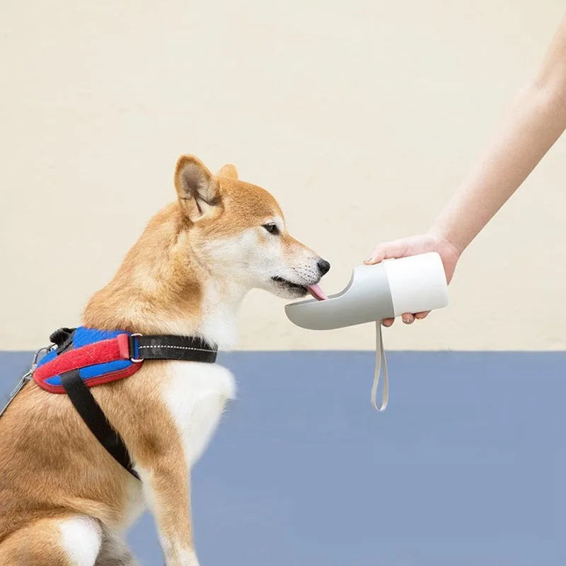 Moestar rocket-shaped pet drinking cup in white with grey accents showing water outlet and lock button