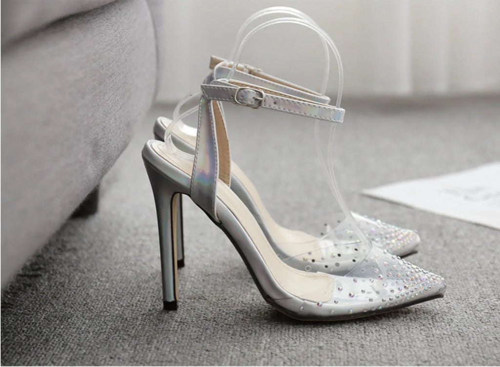 Women's pointed toe stiletto sandals with a diamond embellishment on the PVC upper and an adjustable ankle strap.