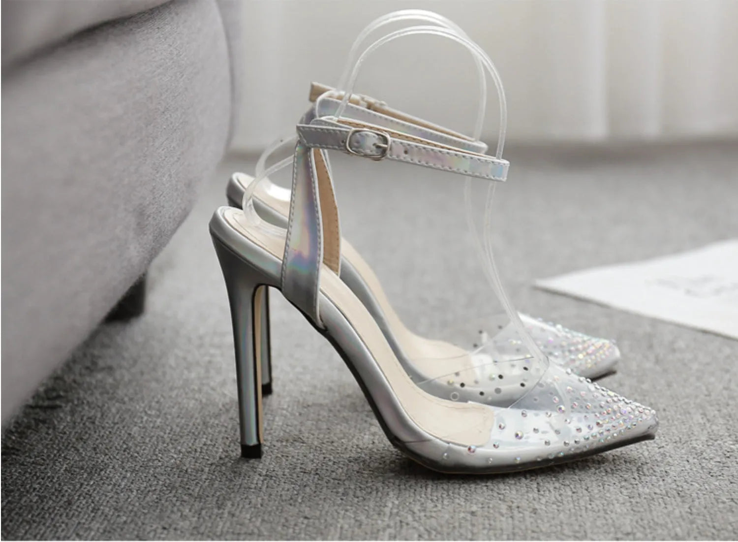 Women's pointed toe stiletto sandals with a diamond embellishment on the PVC upper and an adjustable ankle strap.