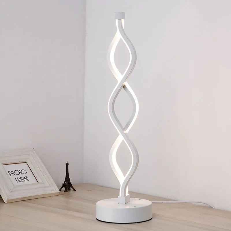 Modern LED desk lamp with aluminium metal body and acrylic mask, gold colour, on a desk