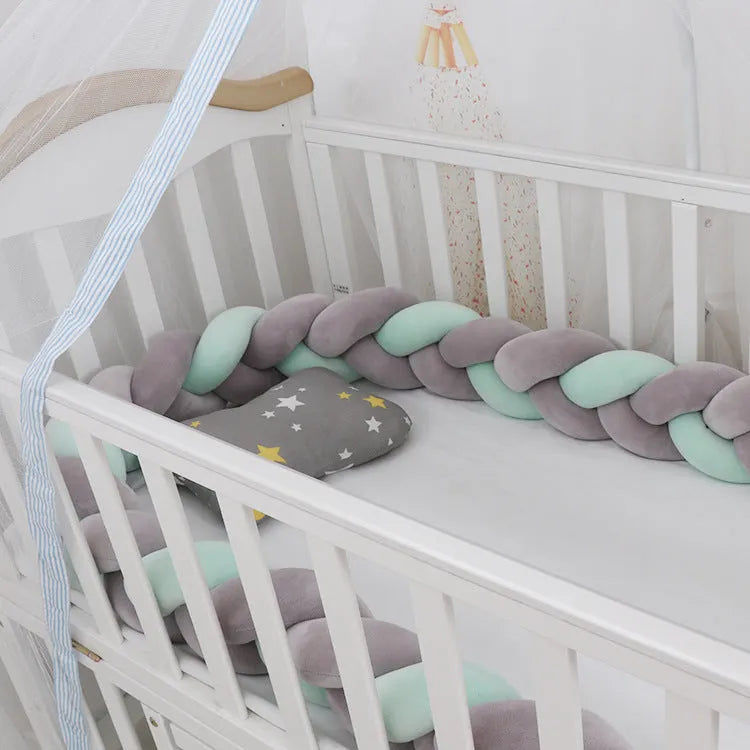 Braided knot style crib bumper in spandex velvet, wrapped around white cot rails in a nursery.