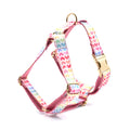 Pink dog harness with gold buckle and heart-shaped stone decoration on white background