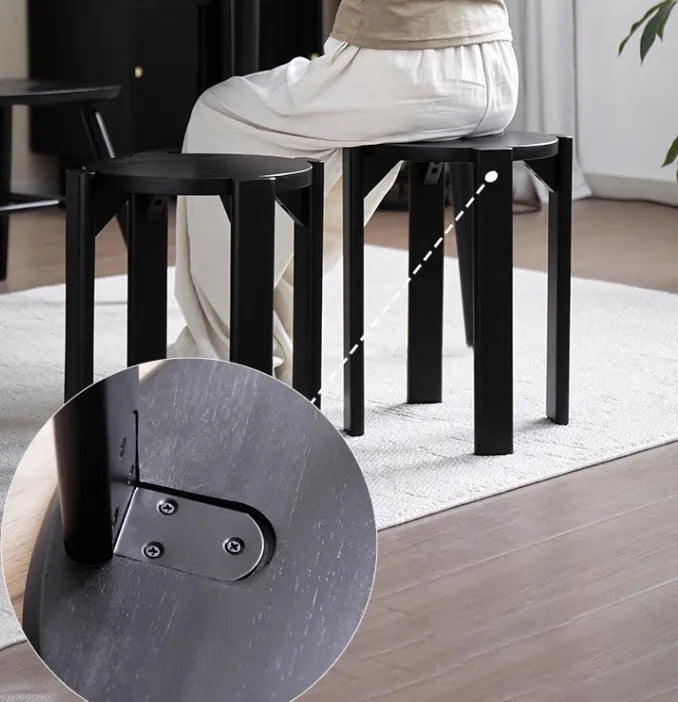 Two stackable round iron stools with splayed legs in a modern kitchen, showing smoked black and cream white colour options.