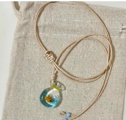 Women's necklace with a blue hand-painted fish charm on a beige cotton and linen clavicle chain.