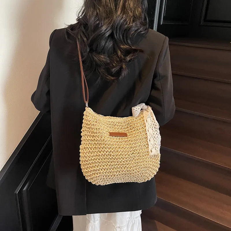 Women's woven straw messenger bag in khaki colour, showing hollowed texture and single shoulder strap.