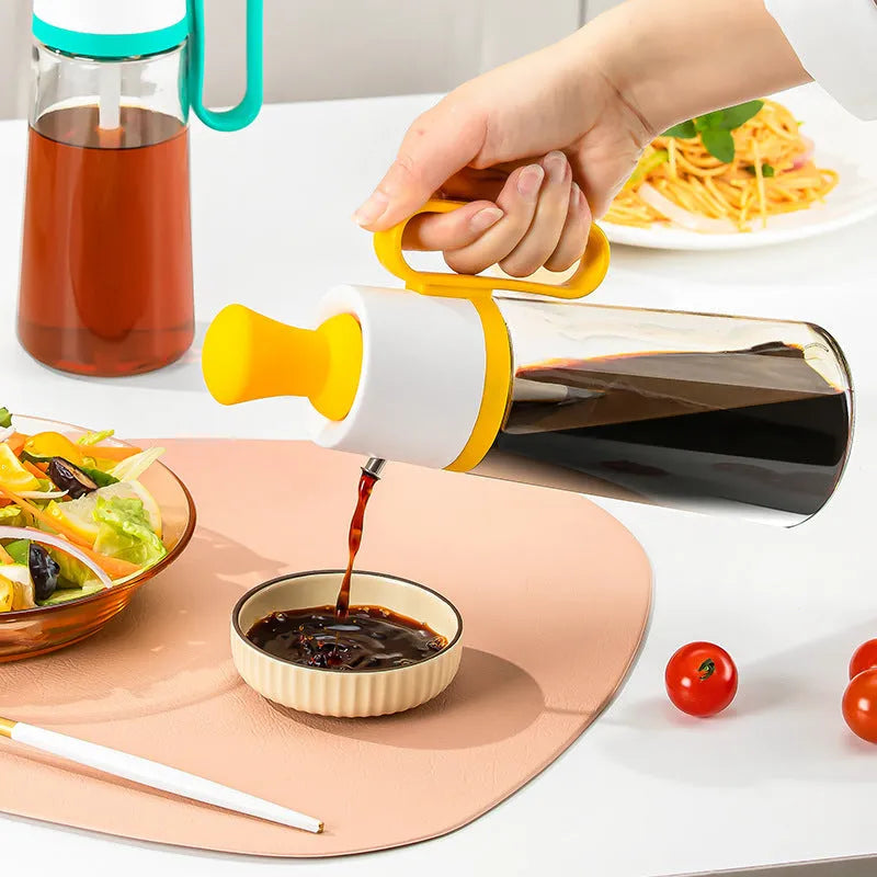 550ml clear glass oil dispenser bottle with stainless steel spray nozzle and a yellow silicone brush head attached.