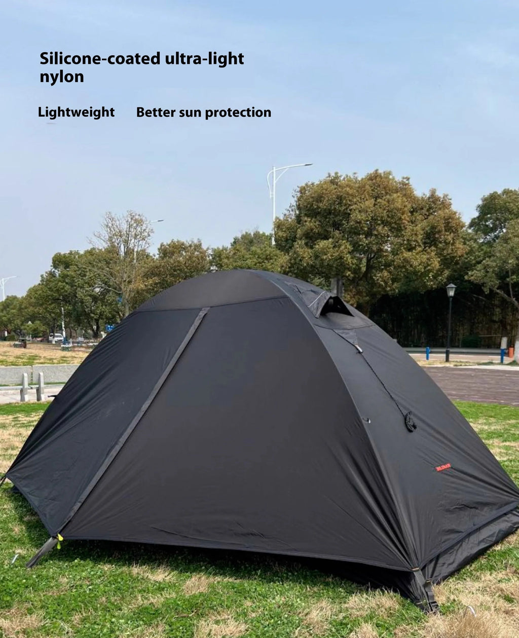 Single person orange double-layer hiking tent pitched in a field with aluminium poles visible.