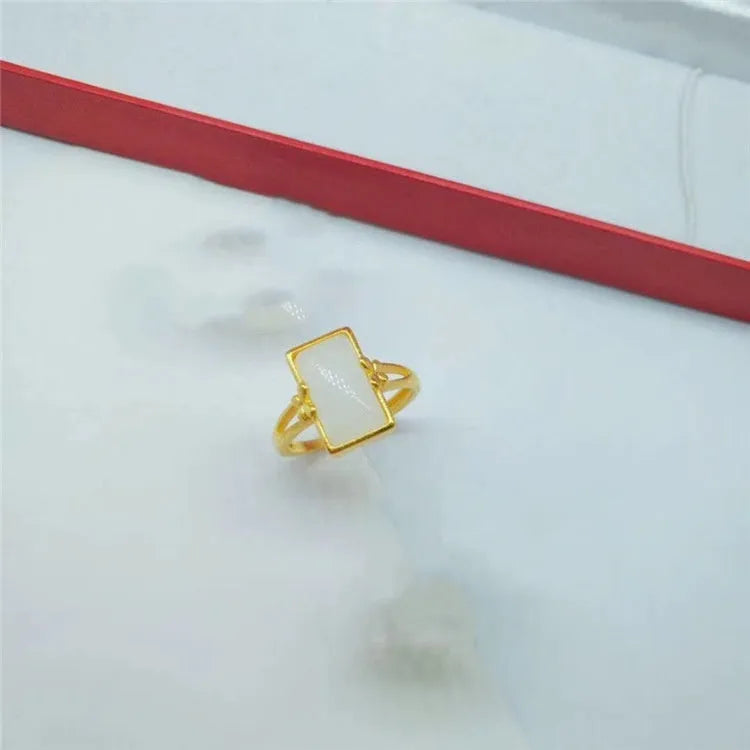 Close-up of an adjustable brass gold-plated ring with an electroplated finish and a green artificial gemstone inlay.