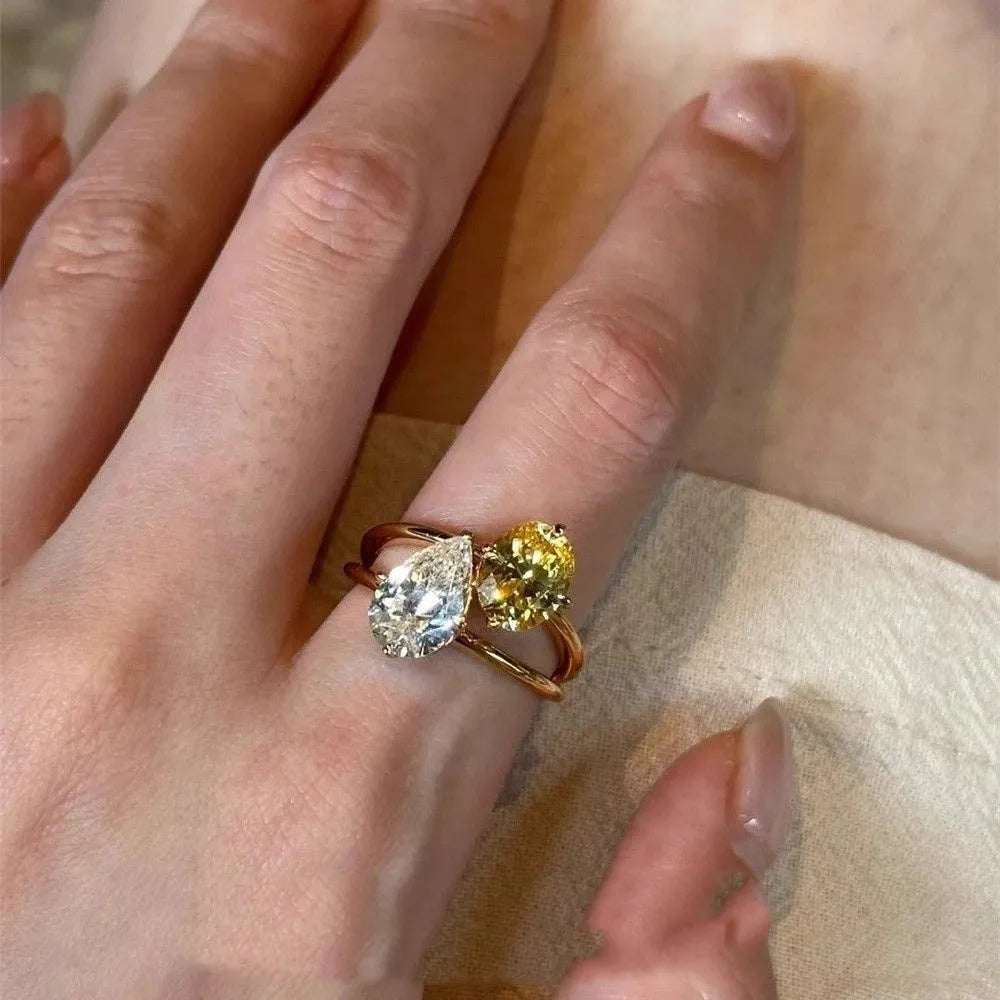 Geometric open-back silver ring with large central pear-cut clear zircon stone on a model's hand.