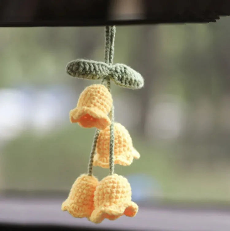 Green and white crocheted wool car plant decoration with a white hanging rope.